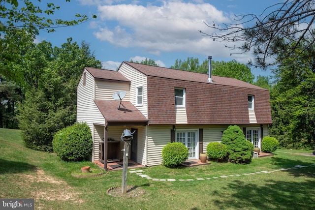 back of house featuring a yard, a shingled roof, and a gambrel roof