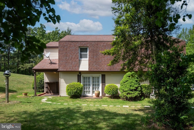 back of house with a lawn and roof with shingles