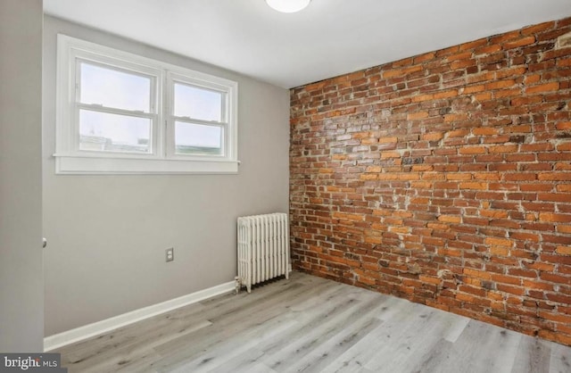 5915 Palmetto St, Philadelphia, PA 19120 - spare room featuring baseboards, brick wall, wood finished floors, and radiator