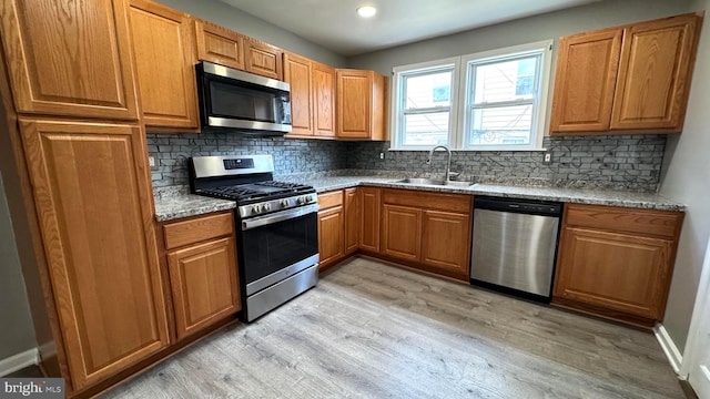 5915 Palmetto St, Philadelphia, PA 19120 - kitchen featuring decorative backsplash, light stone countertops, a sink, light wood finished floors, and appliances with stainless steel finishes