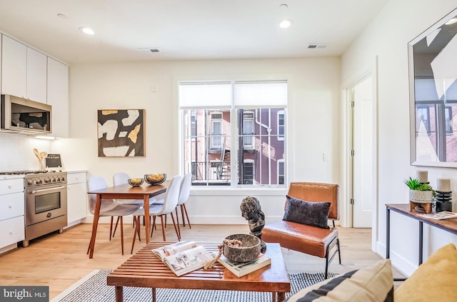living area with light wood-style floors, visible vents, and a healthy amount of sunlight