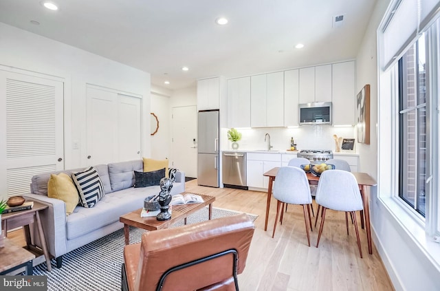 living area with recessed lighting, visible vents, and light wood-type flooring