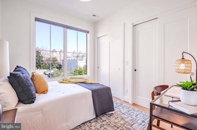 bedroom with light wood-style flooring and visible vents
