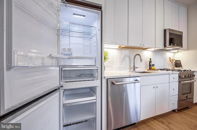 kitchen featuring light wood-style floors, a sink, white cabinetry, and appliances with stainless steel finishes