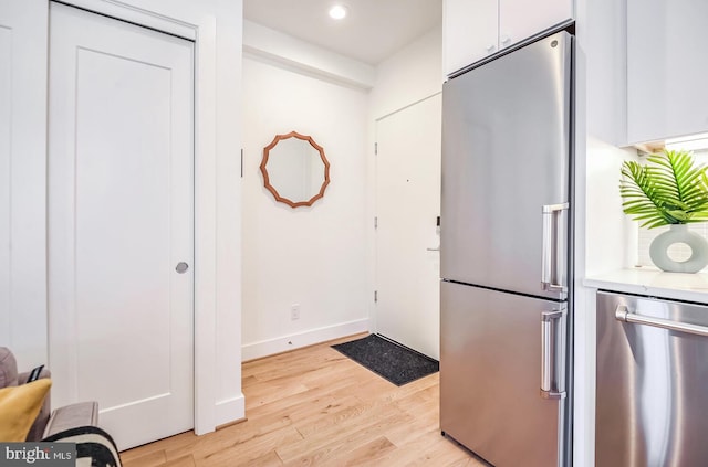 kitchen featuring recessed lighting, stainless steel appliances, light countertops, light wood-type flooring, and white cabinetry