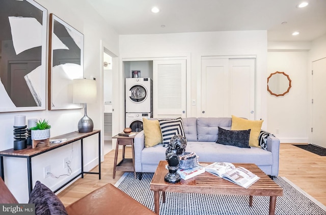 living room with baseboards, wood finished floors, stacked washer and dryer, and recessed lighting