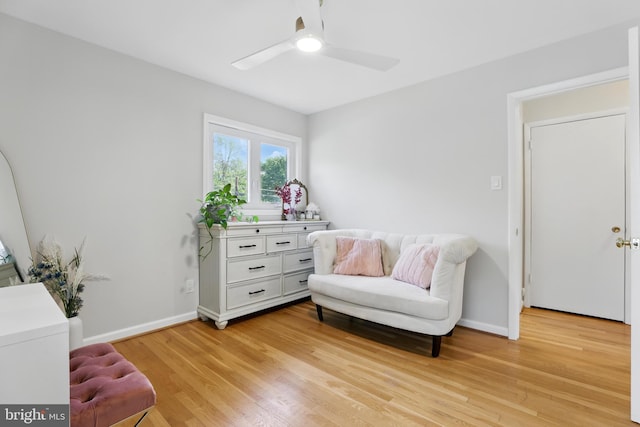 living area with light wood finished floors, ceiling fan, and baseboards