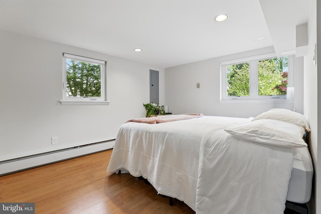 bedroom featuring recessed lighting, electric panel, baseboard heating, and wood finished floors