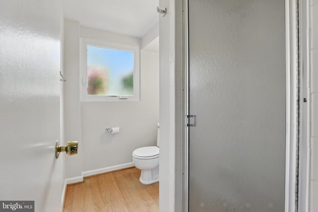 full bath with baseboards, wood finished floors, toilet, and a stall shower