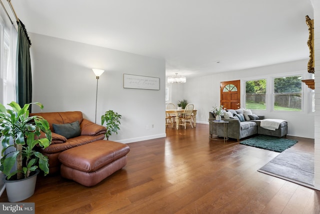 living area featuring an inviting chandelier, wood finished floors, and baseboards