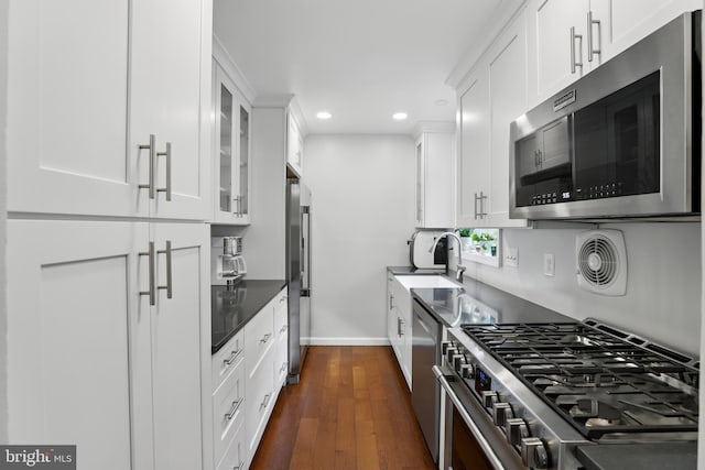 kitchen featuring recessed lighting, a sink, stainless steel appliances, white cabinetry, and baseboards