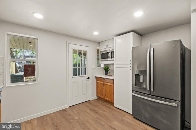 kitchen featuring light countertops, stainless steel appliances, light wood finished floors, and plenty of natural light