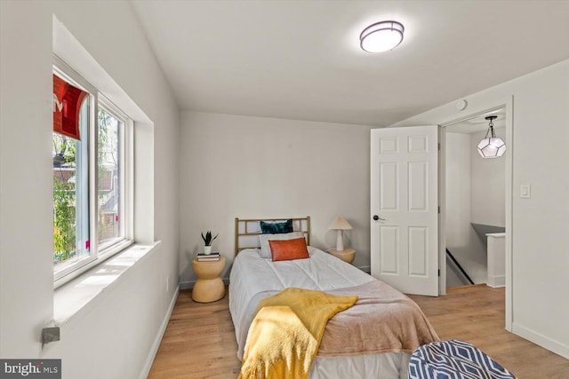 bedroom featuring light wood finished floors, baseboards, and baseboard heating