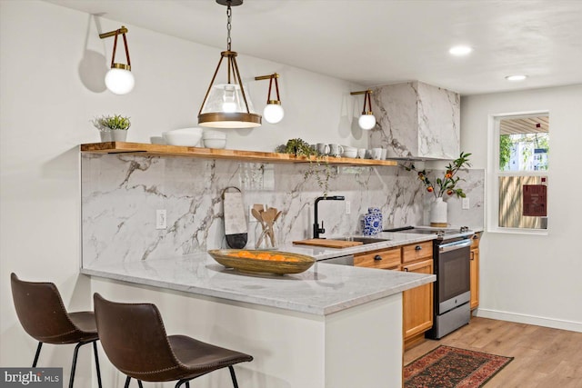 kitchen featuring open shelves, a sink, stainless steel range with electric cooktop, light wood finished floors, and backsplash
