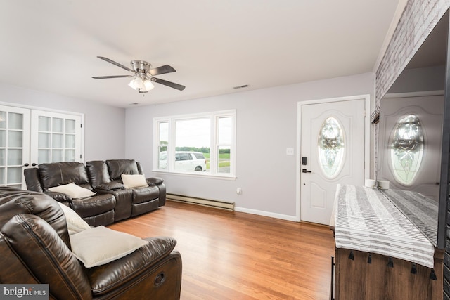 living area featuring baseboard heating, light wood finished floors, french doors, a ceiling fan, and visible vents
