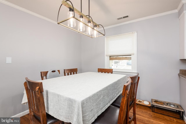 dining space with crown molding, baseboards, visible vents, and wood finished floors