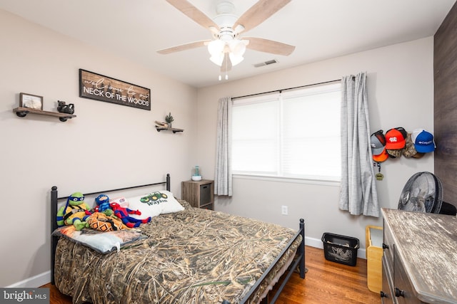 bedroom with baseboards, ceiling fan, wood finished floors, and visible vents
