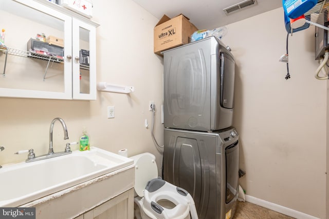washroom with laundry area, visible vents, stacked washing maching and dryer, tile patterned floors, and a sink