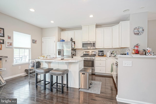 kitchen featuring appliances with stainless steel finishes, decorative backsplash, a breakfast bar, and white cabinets
