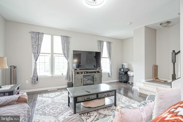living area featuring baseboards, visible vents, and wood finished floors