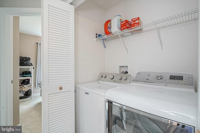 clothes washing area with separate washer and dryer, laundry area, and light colored carpet