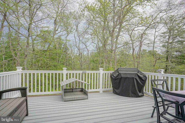 deck with a wooded view and area for grilling