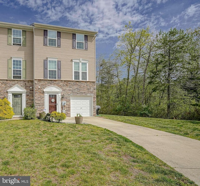 view of front of home with an attached garage, a front yard, stone siding, and concrete driveway
