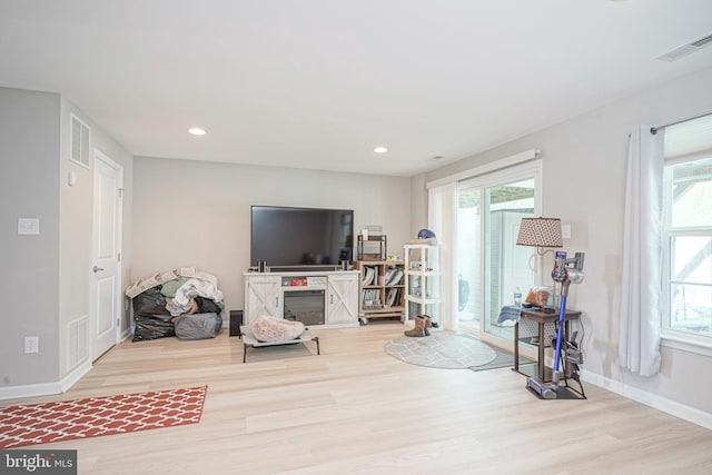 living room with baseboards, visible vents, and wood finished floors