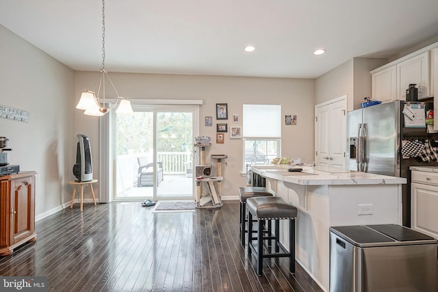 kitchen with an inviting chandelier, a kitchen island, baseboards, a breakfast bar area, and dark wood finished floors