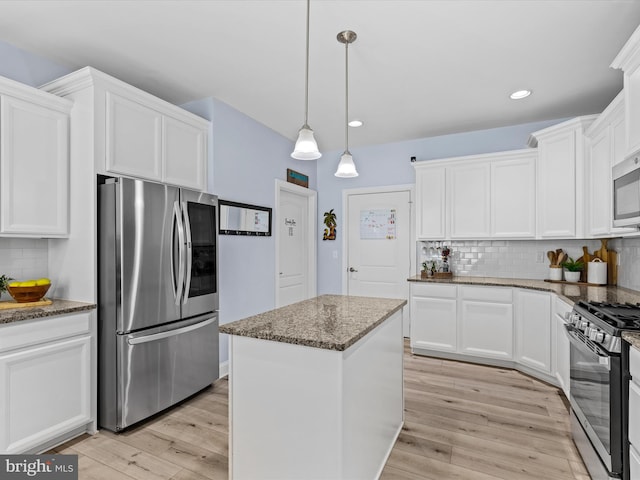 kitchen with stainless steel appliances, dark stone countertops, decorative backsplash, and white cabinetry