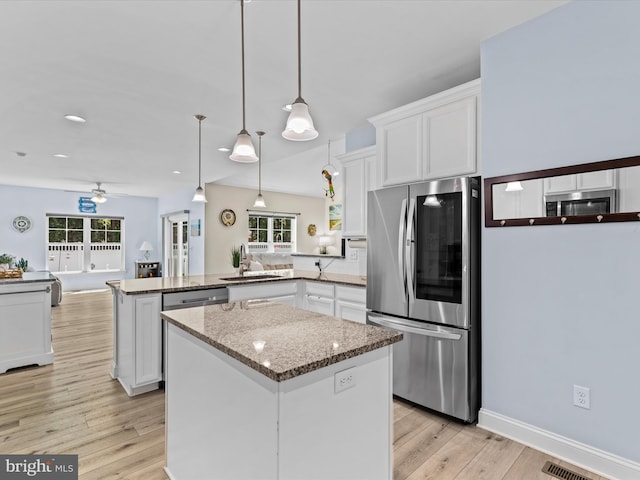 kitchen featuring a peninsula, white cabinetry, a ceiling fan, light stone countertops, and appliances with stainless steel finishes