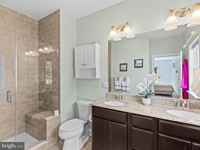 ensuite bathroom featuring a stall shower, a sink, double vanity, and toilet