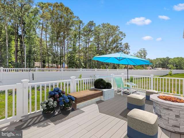 wooden terrace featuring a lawn, an outdoor fire pit, and fence