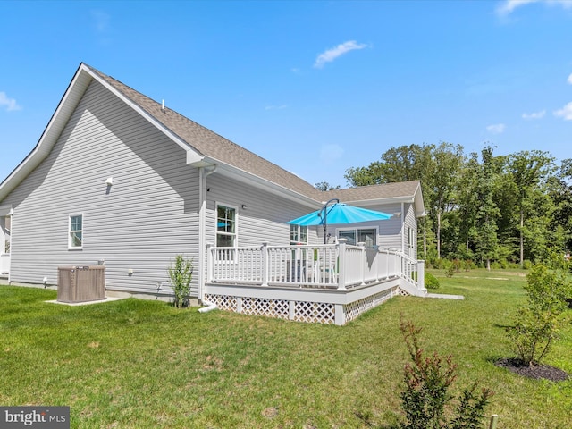 rear view of property featuring cooling unit, a yard, roof with shingles, and a wooden deck