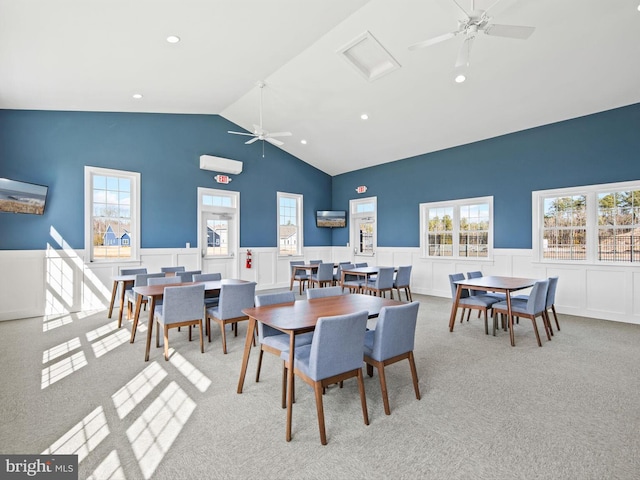 carpeted dining room with plenty of natural light, a decorative wall, a wainscoted wall, and ceiling fan