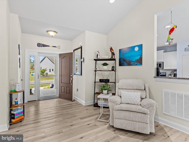 entryway featuring baseboards, vaulted ceiling, visible vents, and light wood-type flooring