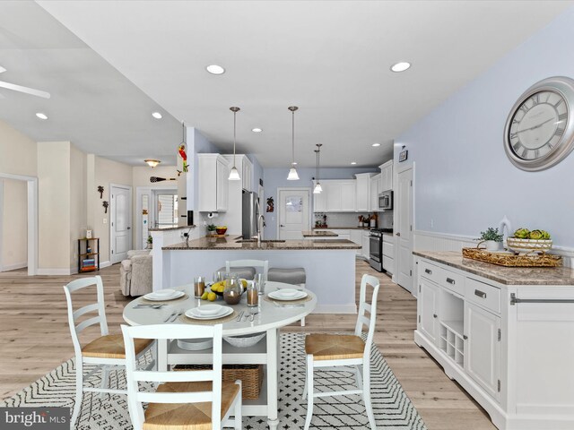 dining room featuring wainscoting, recessed lighting, and light wood-type flooring