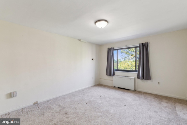 unfurnished room featuring radiator, light colored carpet, and baseboards