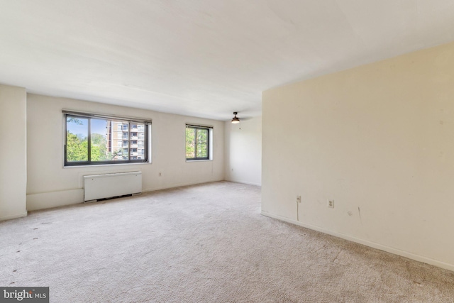 unfurnished room with radiator, carpet, and baseboards