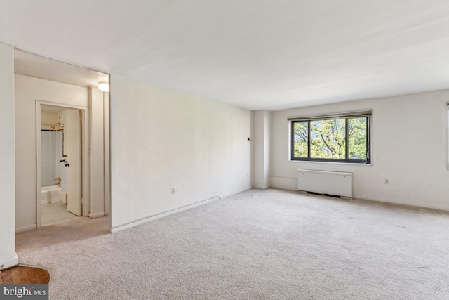 spare room with radiator, carpet, and baseboards