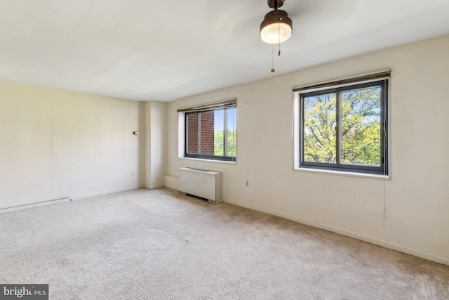 carpeted spare room featuring radiator heating unit and baseboards