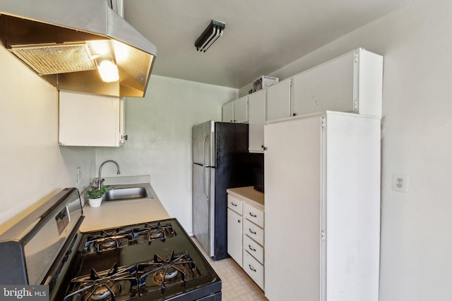 kitchen with under cabinet range hood, appliances with stainless steel finishes, light countertops, and a sink