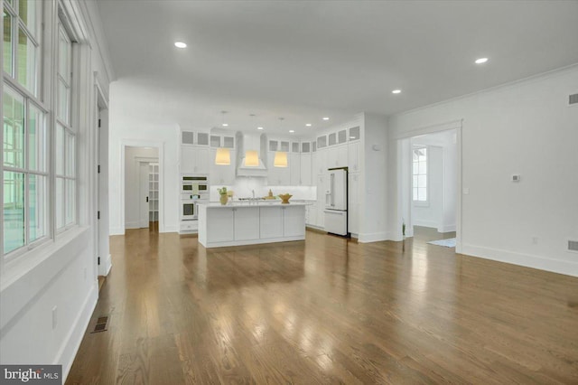 unfurnished living room featuring visible vents, a sink, baseboards, and dark wood-type flooring