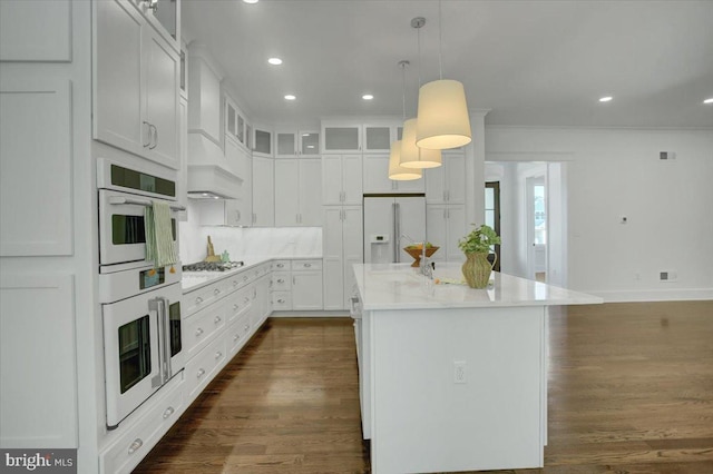 kitchen featuring a center island, dark wood-style flooring, white appliances, and white cabinetry