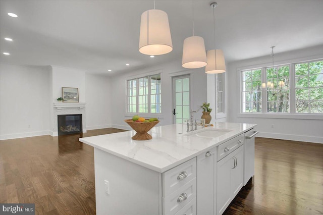 kitchen with a sink, baseboards, dark wood-type flooring, and a healthy amount of sunlight