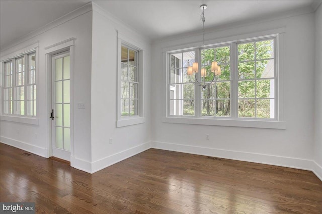 unfurnished dining area with dark wood-style flooring, a chandelier, baseboards, visible vents, and ornamental molding
