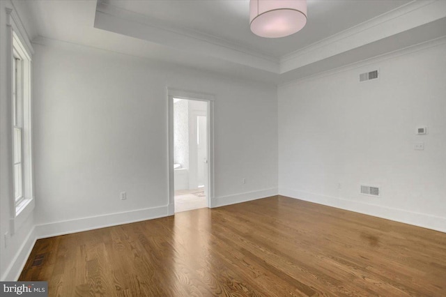 unfurnished room featuring crown molding, visible vents, and a raised ceiling
