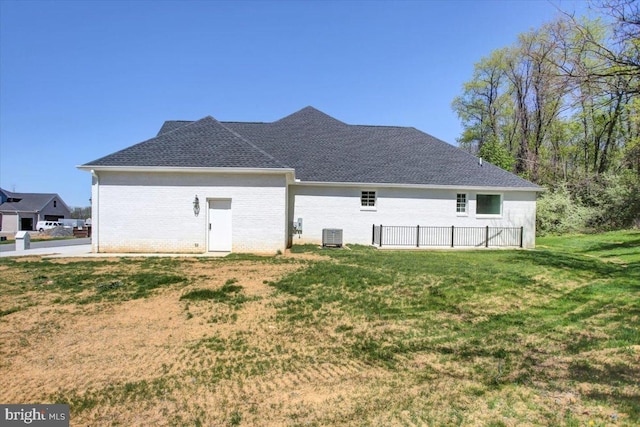 rear view of house featuring a yard, roof with shingles, and central air condition unit