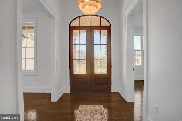 foyer featuring baseboards, dark wood-style flooring, crown molding, and french doors