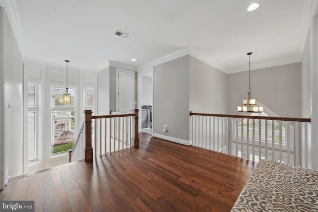 corridor with an inviting chandelier, visible vents, wood finished floors, baseboards, and an upstairs landing